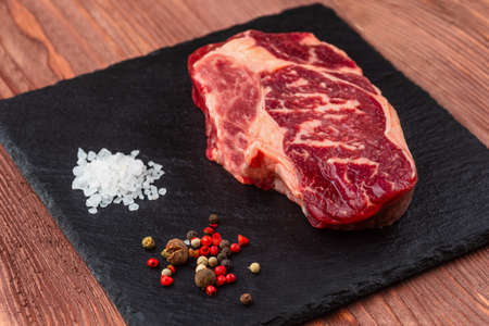 Fresh raw Prime Black Angus beef steaks on stone board: Striploin, Rib Eye. Top view. On a dark backgroundの写真素材