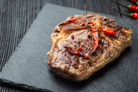 Fresh raw Prime Black Angus beef steaks on stone board: Striploin, Rib Eye. Top view. On a dark backgroundの写真素材