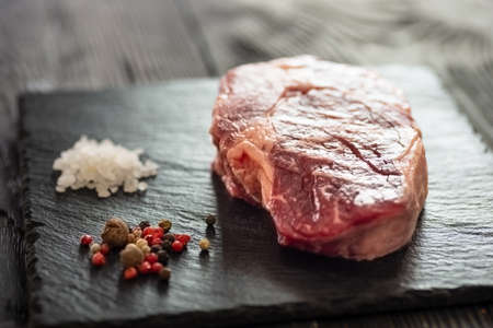 Fresh raw Prime Black Angus beef steaks on stone board: Striploin, Rib Eye. Top view. On a dark backgroundの写真素材