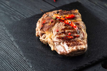 Fresh raw Prime Black Angus beef steaks on stone board: Striploin, Rib Eye. Top view. On a dark backgroundの写真素材