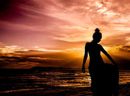 Portrait of young woman in dress as silhouette by the seaの写真素材
