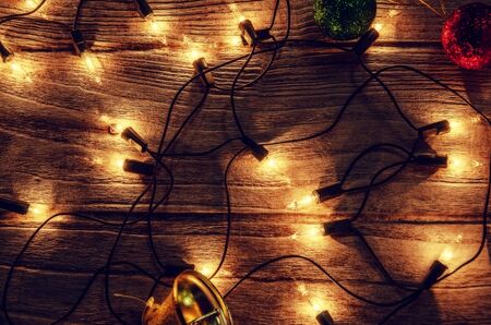 Christmas rustic light bulb background with jingle bells and ball on vintage wood panel backgroundの写真素材