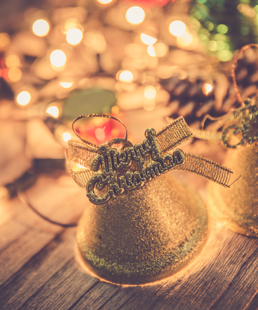 christmas jingle golden bell deco with rusty gold light bulb on wood background with copy spaceの写真素材