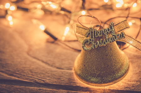 christmas jingle golden bell deco with rusty gold light bulb on wood background with copy spaceの写真素材