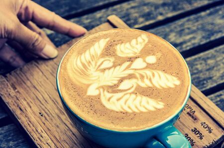 vintage latte art coffee cup on wood backgroundの写真素材