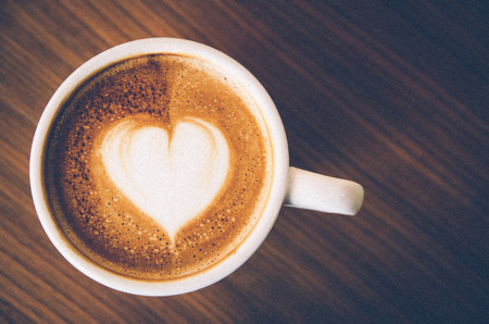 Close up Coffee latte art on wood background , vintage with grainの写真素材