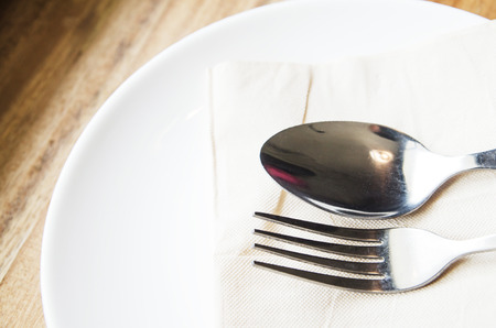 Vintage toned picture of ancient fork and spoon on the plate lying at the old table.の写真素材