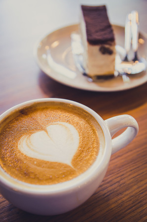 cup of coffee and cake on table in cafeの写真素材