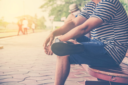 side view of man traveler sitting on wood chair in train stationの写真素材