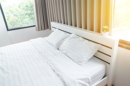 odern bedroom with brown and white pillow on bed (bed)の写真素材