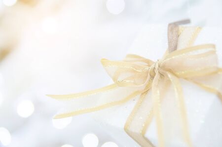 white Christmas gift box  with gold ribbon  and copyspace for your greeting or wishesの写真素材