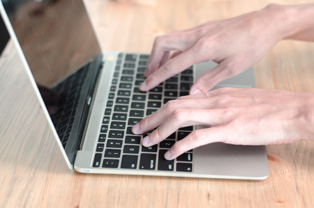 Female hand holding keyboard while working on computerの写真素材