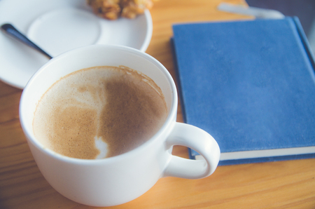 Coffee cup on wood table with blue blook の写真素材