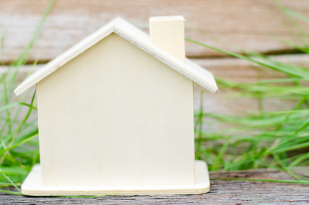 Brown wooden house model on wood table over white wall background with copy space, real estate conceptの写真素材