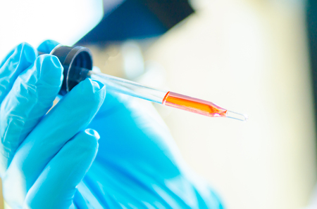 A pipette dropping sample into a test tube,abstract science backgroundの写真素材
