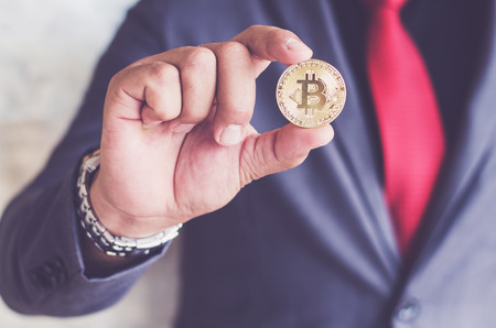 Cryptocurrency golden bitcoin coin. Man holding in hand symbol of crypto currency - electronic virtual money for web banking and international network payment, selective focus, tonedの写真素材