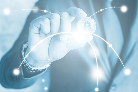 Cryptocurrency golden bitcoin coin. Man holding in hand symbol of crypto currency - electronic virtual money for web banking and international network payment, selective focus, tonedの写真素材