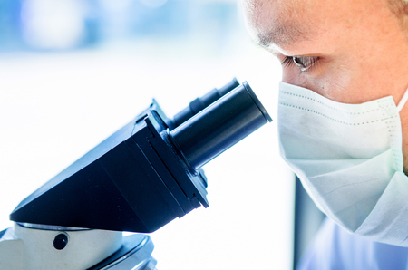 Young scientist looking through a microscope in a laboratory. Young scientist doing some research.の写真素材
