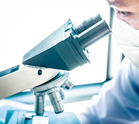 Young scientist looking through a microscope in a laboratory. Young scientist doing some research.の写真素材