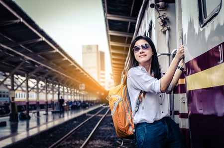 Girl wearing backpack holding map, waiting for a train. Traveling in Bangkok Thailand. Travel conceptの写真素材