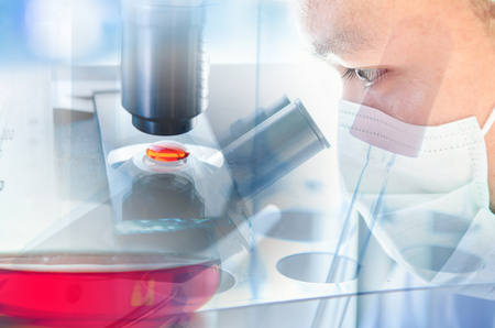 Young scientist looking through a microscope in a laboratory. Young scientist doing some research.の写真素材