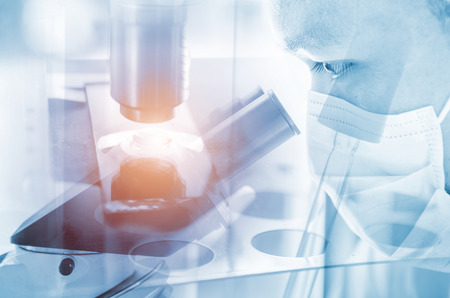 Young scientist looking through a microscope in a laboratory. Young scientist doing some research.の写真素材