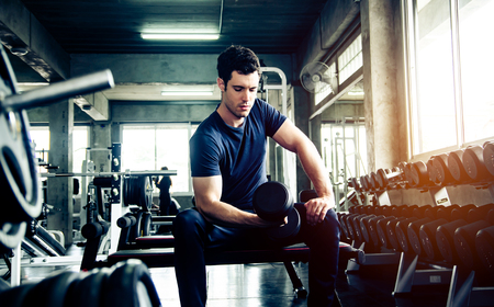 sport, fitness, bodybuilding, lifestyle and people concept - man exercising work out and flexing muscles in gymの写真素材