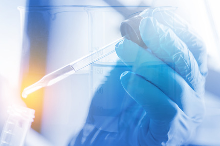 A pipette dropping sample into a test tube,abstract science backgroundの写真素材