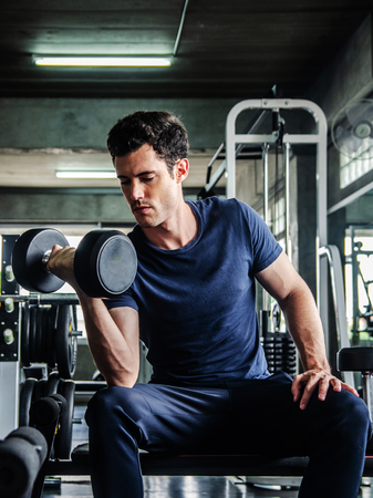 sport, fitness, bodybuilding, lifestyle and people concept - man exercising work out and flexing muscles in gymの写真素材