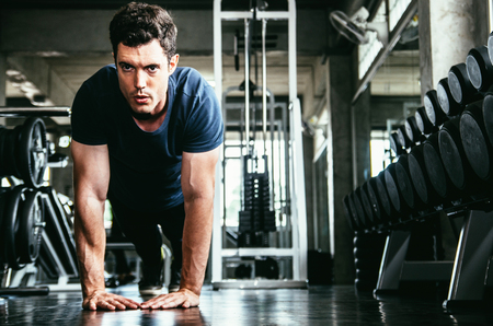 sport, fitness, bodybuilding, lifestyle and people concept - man exercising work out and flexing muscles in gymの写真素材