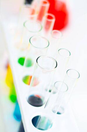 top view of laboratory equipments. A blue liquid watch glass, flask, test tubes and beaker on the white tableの写真素材