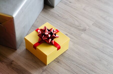 yellow Christmas gift box  with red ribbon  and copyspace for your greeting or wishesの写真素材