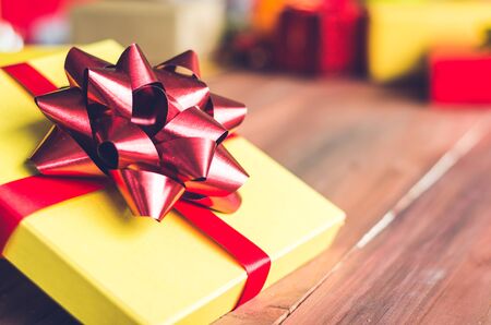 golden gift box and red ribbon on color backgroundの写真素材