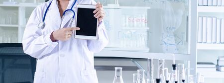 Doctor working with laptop computer and writing on paperwork. Hospital background.の写真素材