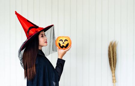 Halloween Witch with a magic Pumpkin ,  Beautiful young woman in witches hat and costumeの写真素材