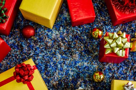 golden gift box and red ribbon on color backgroundの写真素材