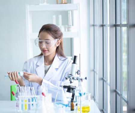 young  Scientist woman  using alcohol gel for cleaeing hand before working in laboratoryの写真素材