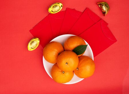 Accessories on Lunar New Year & Chinese New Year vacation concept background.Orange in white plate with red pocket moneyの写真素材
