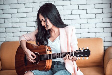 woman playing guitar on sofa .の写真素材