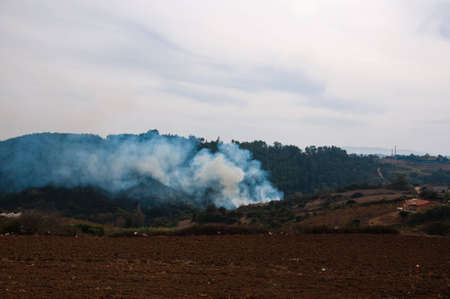 Fire in the mountains of smoke in the forest village nature landscape fearの写真素材