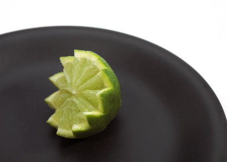 GREEN LEMON citrus aurantifolia ON PLATEの写真素材