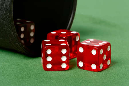 Red dice thrown from dice cup onto felt table