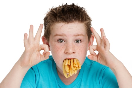 Young boy with a mouth full of chips fries. Isolated on white background.の写真素材