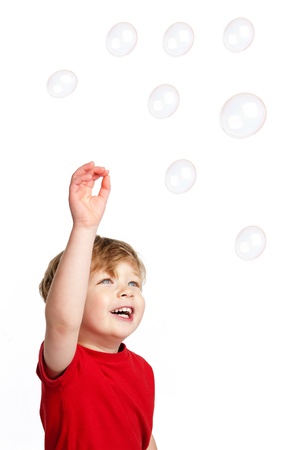 Cute Happy boy playing with bubbles shot in the studio on a white background.の写真素材