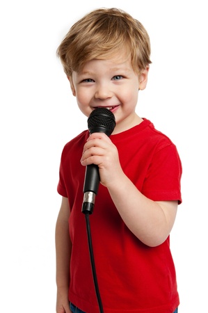 Smiling happy boy singing into a microphone shot in the studio on a white background.の写真素材