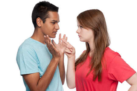 Teenagers in arguement. Girl accusing. Boy defending. Studio shot. White background.の写真素材