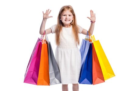 Girl waiving to camera with lots of shopping. Isolated in studio on white background.の写真素材