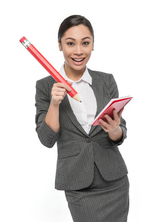 Woman with big pencil writing on red pad of paper happy expression. Studio shot on white background.の写真素材