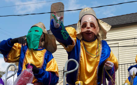 A masked rider throws beads from a float to revelers during a Mardi Gras parade in New Orleansの写真素材