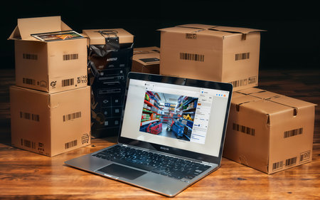 Laptop with online shopping website on the screen and cardboard boxes on the tableの素材